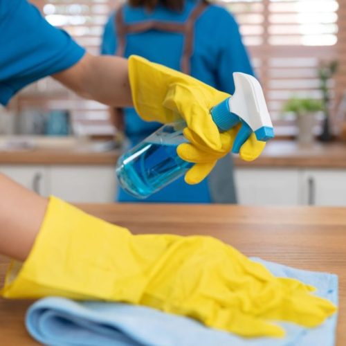 Close up hand holding bottle spray and wiping with microfiber cloth in kitchen room at home